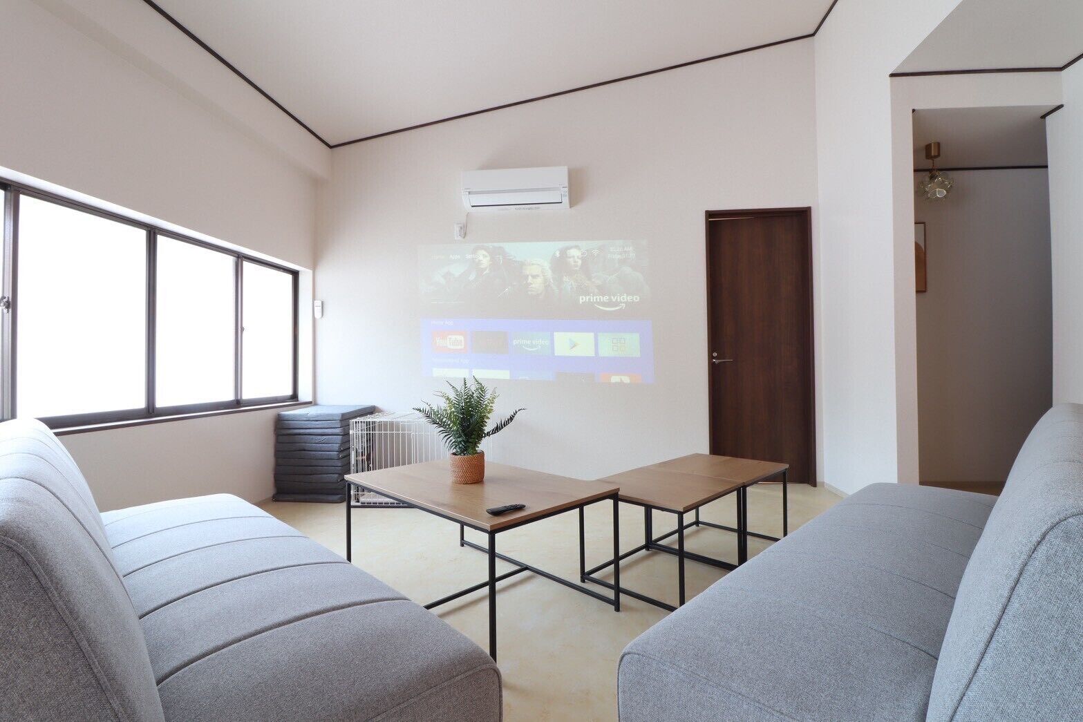Uma sala de estar moderna com sofá, mesa de centro e tela de projetor exibindo uma interface de vídeo.