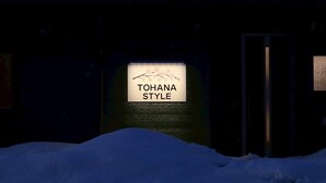 A sign reading "TOHANA STYLE" in front of a building with a dark facade and a snow-covered ground. - TOHANASTYLE (Hanamaki)