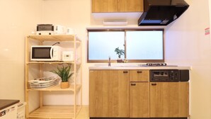 A compact kitchen with wooden cabinets, a microwave, a dishwasher, and a window with a view. - TOHANASTYLE (Hanamaki)