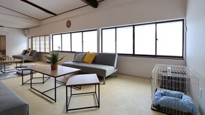 A spacious living room with a grey sofa, a coffee table, and a pet cage. - TOHANASTYLE (Hanamaki)