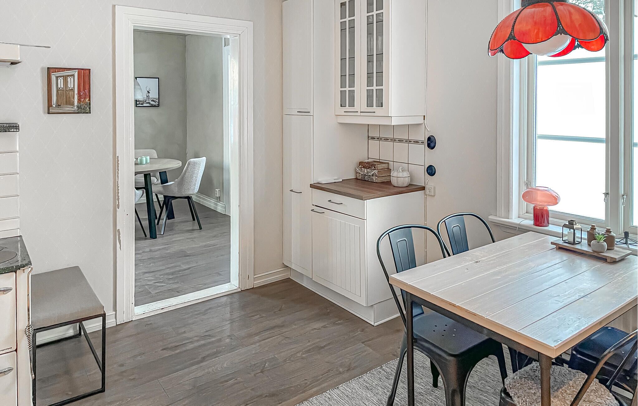 Une cuisine moderne avec des meubles blancs, un plan de travail en bois et un coin repas comprenant une table et des chaises en bois.