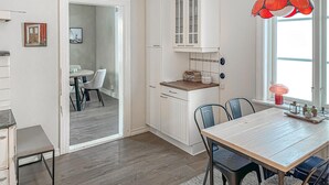 Una cocina moderna con armarios blancos, encimera de madera y una zona de comedor con mesa y sillas de madera.