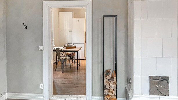Un pasillo con una puerta blanca que da a un comedor con mesa y sillas.