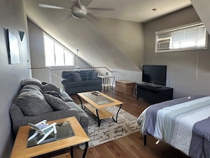 Ein Loft-Zimmer mit einer Couch, einem Couchtisch, einem Fernseher und einem Bett.