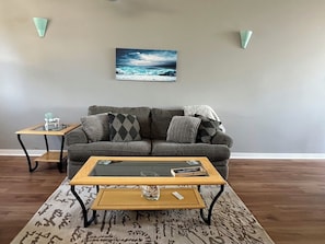Ein Wohnzimmer mit einer Couch, zwei Beistelltischen, einem Couchtisch und einem Wandbild.