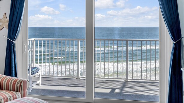Une pièce dotée d’une grande porte-fenêtre coulissante donnant sur un balcon avec vue sur l’océan.
