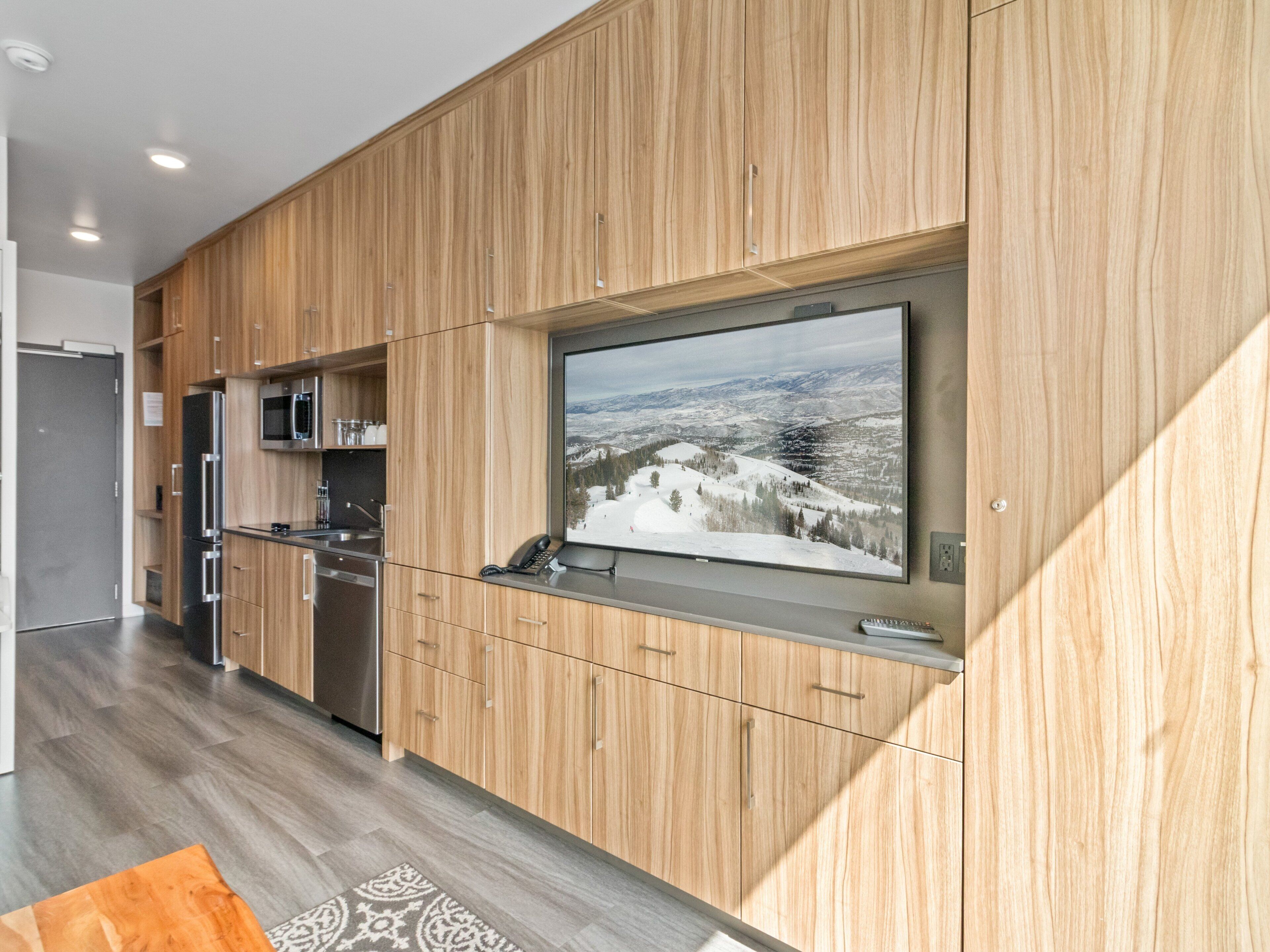 A modern kitchen with wooden cabinetry, stainless steel appliances, and a large window with a scenic view.