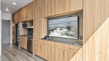 A modern kitchen with wooden cabinetry, stainless steel appliances, and a large window with a scenic view.