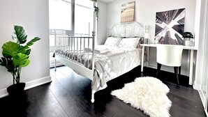 Een moderne slaapkamer met een bed, bureau en een groot raam.