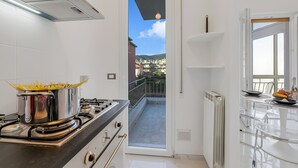 Eine Küche mit Herd, Töpfen und Blick auf einen Balkon.