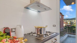 Eine Küche mit Herd, Spaghetti in einem Topf und einem Fenster mit Blick auf eine Wohngegend.