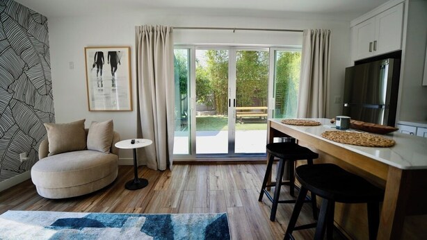 Et moderne køkken med en stor ø, en sofa og et spiseområde med barstole.