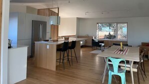 Une cuisine moderne dotée d’un îlot central, de meubles en bois et d’une grande fenêtre qui laisse entrer la lumière naturelle.