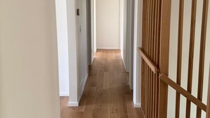 Un long couloir étroit, doté d’un plancher en bois et de murs blancs.