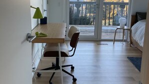 Une pièce comprenant un bureau en bois, une chaise, un lit et un balcon doté d’une balustrade.
