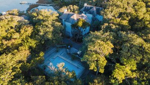 Vista aérea de una zona residencial con casas rodeadas de árboles frondosos, un muelle y una pequeña piscina.