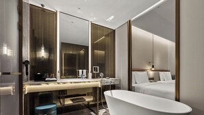A modern bathroom with a freestanding bathtub, a vanity with a mirror, and a large mirror reflecting the room. - Wanda Vista Changchun International Movie Metropolis (Changchun)
