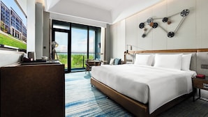 A modern hotel room with a large bed, a desk, a chair, and a view of the outdoors. - Wanda Vista Changchun International Movie Metropolis (Changchun)