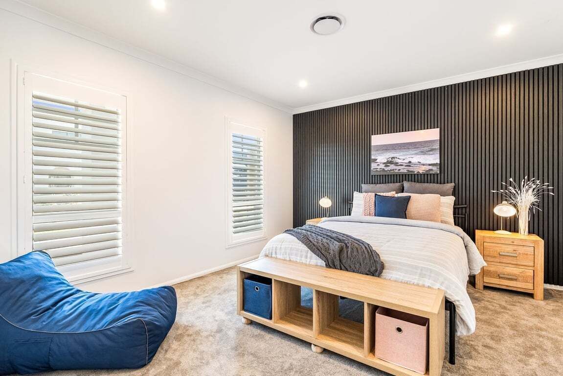 A modern bedroom with a bed, bedside tables, a bench, and storage units.