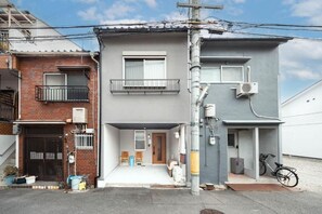A two-story residential building with a balcony, a garage, and a bicycle parked outside. - TAISHO-7 (Osaka)