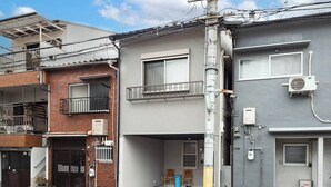 A residential building with a grey facade, a visible air conditioning unit, and a metal staircase leading to a balcony. - TAISHO-7 (Osaka)