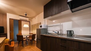 A compact kitchen with a dining area, wooden cabinets, a microwave, and a kettle. - TAISHO-7 (Osaka)