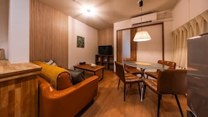 A modern living room with a sofa, a dining table with chairs, a TV, and a ceiling light. - TAISHO-7 (Osaka)