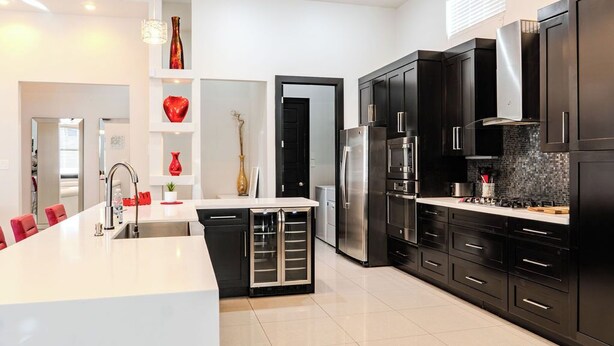 A modern kitchen with black cabinets, stainless steel appliances, and a white island. - Modern upscale home with an amazing kitchen. (El Paso)