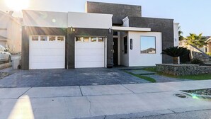 A modern two-story house with a garage, a small front yard, and a stone accent wall. - Modern upscale home with an amazing kitchen. (El Paso)