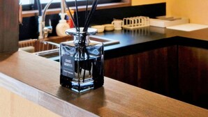A kitchen with a bamboo blind, a glass bottle with reed sticks, a sink, and a window with a view. - Yubikan, Japanese style 80 sq.m. with terrace and garden｜3 min. walk from Tanabe station on the Osaka Tanimachi line｜5 min. direct access to Tennoji shopping area. (大阪市)