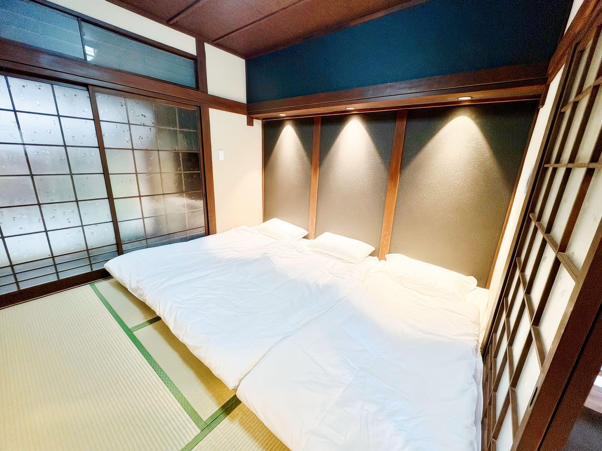 A traditional Japanese room with tatami flooring, a low wooden bed, and shoji screens.