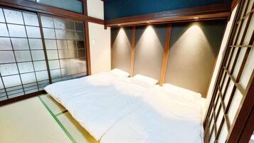 A traditional Japanese room with tatami flooring, a low wooden bed, and shoji screens.