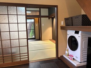 A traditional Japanese room with tatami flooring, a sliding shoji door, and a washing machine.