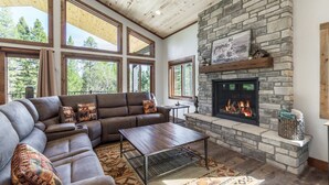 Una sala de estar acogedora con chimenea de piedra, ventanas amplias, un sofá modular y una mesita de centro.