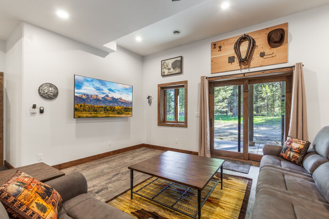 A spacious living room with a large painting, a wooden wall decor, a sofa, and a view through a glass door.