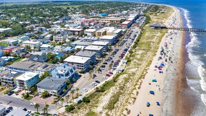A coastal town with a long beach, a pier, and a row of buildings along the shore. - Beachside Retreat, Steps from the Beach | Heated Pool Access (Tybee Island)