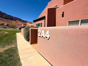 Um prédio residencial com fachada em estuque, com o número '2A4' visível na parede, e uma entrada com calçada.