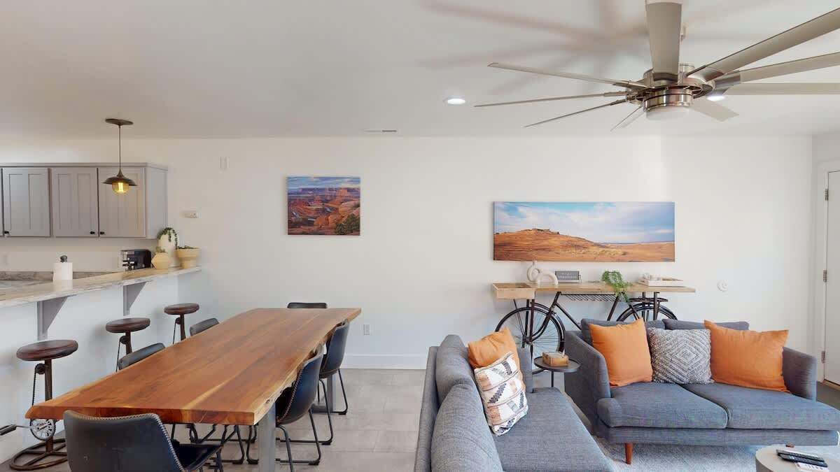 A modern living room with a sofa, a dining table, and a ceiling fan.