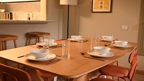 A dining table set with white bowls, plates, and cutlery, surrounded by orange chairs. - Pyramids Haven (Giza Governorate)