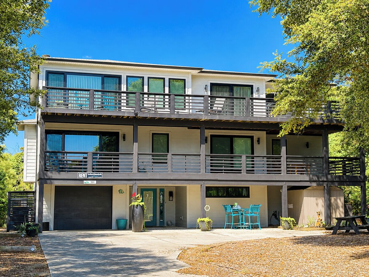 Un bâtiment à deux étages doté d’un balcon, d’un garage et d’un espace extérieur aménagé pour s’asseoir.