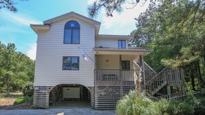 A two-story house with a covered porch and a staircase leading to a second-floor balcony. - HappyTauk - 4 BR Home Near Beach w/Private Pool - Dogs Allowed (Southern Shores)
