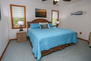 A bedroom with a bed, two bedside tables, a nightstand, a ceiling fan, and a fish decoration on the wall. - One Particular Harbour - 5 BR Single Level Ranch, Private Pool, Canalfront (Southern Shores)