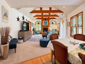 A spacious living room with a fireplace, a television, and a dining area with a table and chairs. - One Particular Harbour - 5 BR Single Level Ranch, Private Pool, Canalfront (Southern Shores)