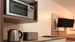 A compact kitchenette with a microwave, toaster, kettle, and a small dishwasher. - Cosy Queen Room Charleville (charleville)