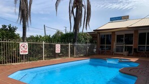 A swimming pool with a no running and no diving sign, surrounded by a fence, with a building labeled 'Charleville Motel' in the background. - Cosy Queen Room Charleville (charleville)