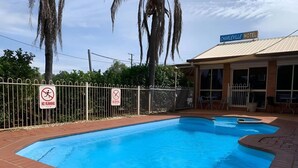 A swimming pool area with a no running and no diving sign, surrounded by a white fence, and a Charleville Motel in the background. - Premium Queen Charleville (charleville)