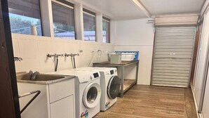 A laundry room with two washing machines, a sink, and a drying rack. - Premium Queen Charleville (charleville)