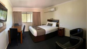 A hotel room with a bed, a desk, a chair, a TV, and an air conditioning unit. - Premium Queen Charleville (charleville)