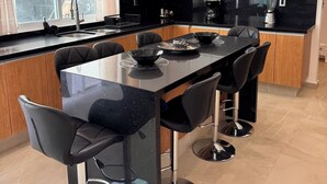 A modern kitchen with a central island, black bar stools, and a large window. - VACATION FAMILY HOME, MODERN HIMALAYA II (Fraccionamiento Lomas de Cocoyoc)