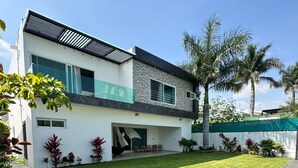 A modern two-story house with a well-maintained lawn and a swimming pool. - VACATION FAMILY HOME, MODERN HIMALAYA II (Fraccionamiento Lomas de Cocoyoc)